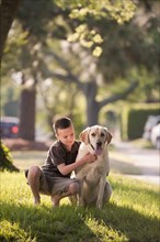 Caucasian boy petting dog in yard