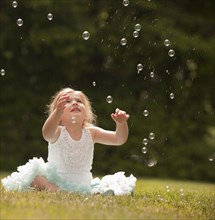 Caucasian girl watching floating bubbles