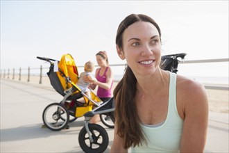 Caucasian mothers with strollers on beach boardwalk