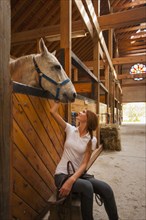 Caucasian girl petting horse in stable