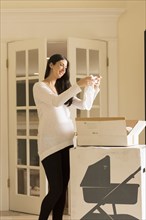 Pregnant Caucasian woman admiring baby clothing