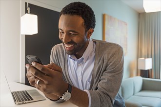 Black man using cell phone in living room