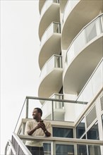 Black man using cell phone on balcony