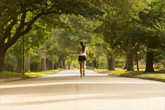 Caucasian woman jogging on neighborhood street