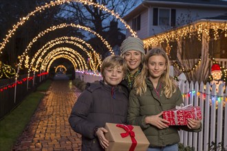 Caucasian family holding Christmas gifts on sidewalk
