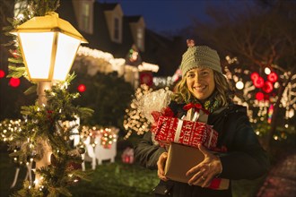 Caucasian woman holding Christmas gifts on sidewalk