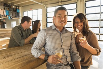 Portrait of smiling couple drinking beer with friends in brew pub