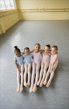 Portrait of smiling girls hugging on floor of ballet studio
