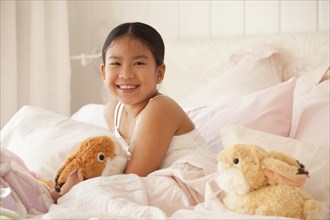 Smiling Asian girl laying in bed