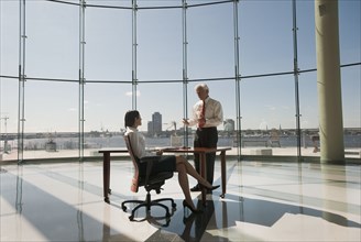 Business people working in large office with glass wall