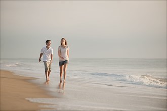 Caucasian brother and sister walking on beach