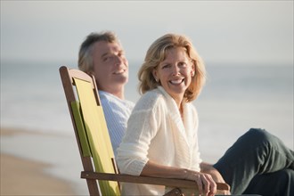 Caucasian couple sitting on folding chairs on beach
