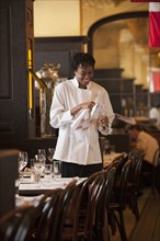 African American waitress checking wine glass in restaurant