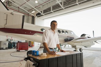 Hispanic man working in airplane hangar