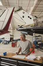 Caucasian man working in airplane hangar