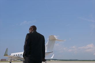 African American businessman standing on airport tarmac