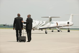 Businessmen walking on airport tarmac