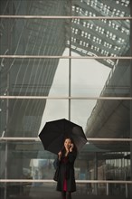 Asian businesswoman with umbrella talking on cell phone