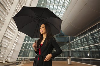 Asian businesswoman underneath umbrella