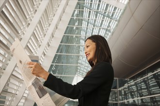 Asian businesswoman reading newspaper