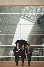 Business people walking together with umbrella
