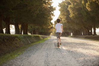 Caucasian boy running on dirt road