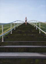 Caucasian woman running up steps