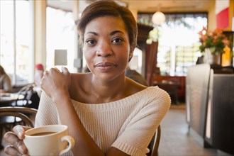 African American woman drinking coffee in cafe