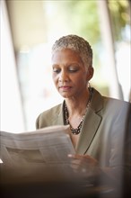 African American businesswoman reading newspaper in cafe