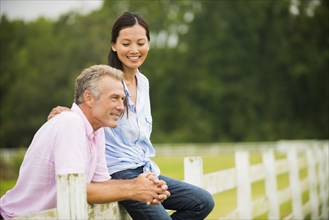 Couple relaxing together on fence