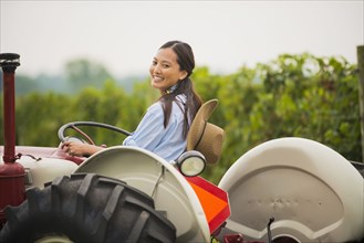 Asian woman driving tractor in field