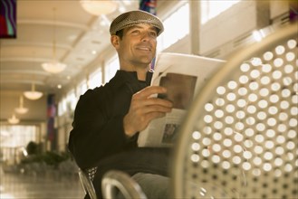 Caucasian man reading newspaper in cafe