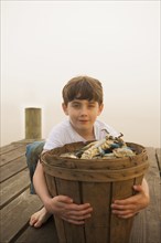 Caucasian boy holding basket of crabs