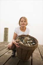 Caucasian girl holding basket of crabs