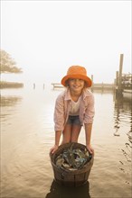 Caucasian girl holding basket of crabs