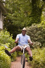 African American man riding bicycle in backyard