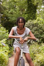 African American woman sitting on bicycle in backyard