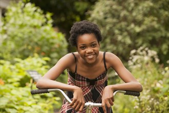 African American girl sitting on bicycle in backyard