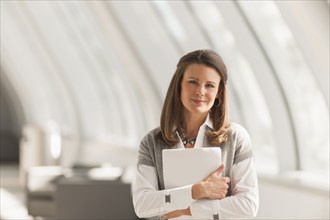 Caucasian businesswoman carrying papers in lobby