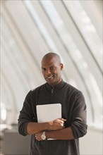African American businessman carrying papers in lobby