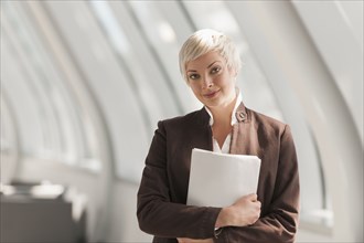 Caucasian businesswoman carrying papers in lobby