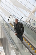 African American businessman smiling on escalator