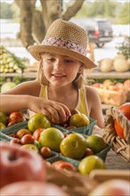 Mixed race girl browsing produce at farmers market