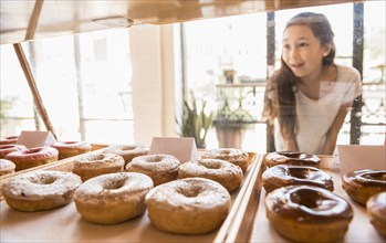 Mixed race girl examining donuts in bakery
