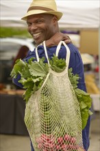 African American man carrying bag of vegetables