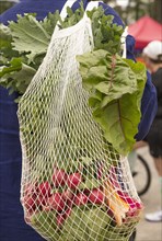African American man carrying bag of produce at market