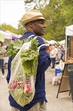 African American man carrying bag of produce at market