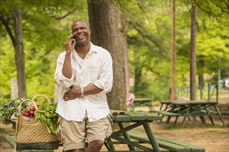 African American man talking on cell phone on picnic table