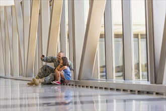 Returning soldier taking selfie with daughter in airport
