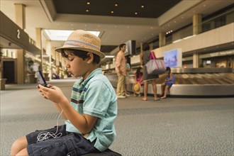 Boy playing on cell phone in airport